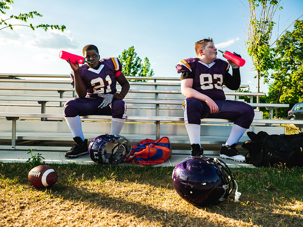 two football players resting during practice and hydrating