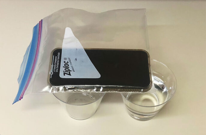 a photo of a cell phone in a plastic bag on top of two glasses of water