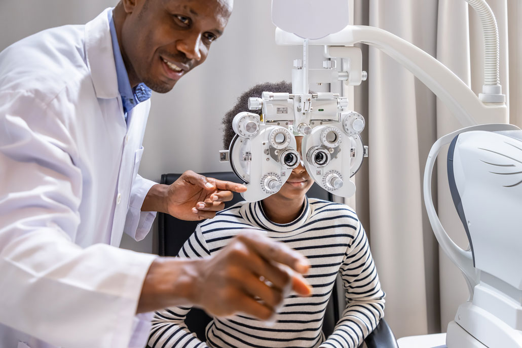 A Black optometrist tests various prescription lenses for his young Black patient.